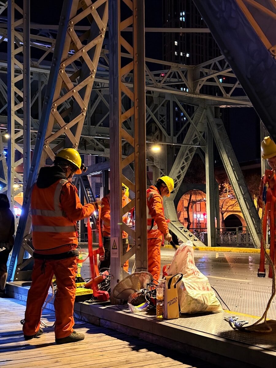 Workers in safety gear perform bridge repairs.